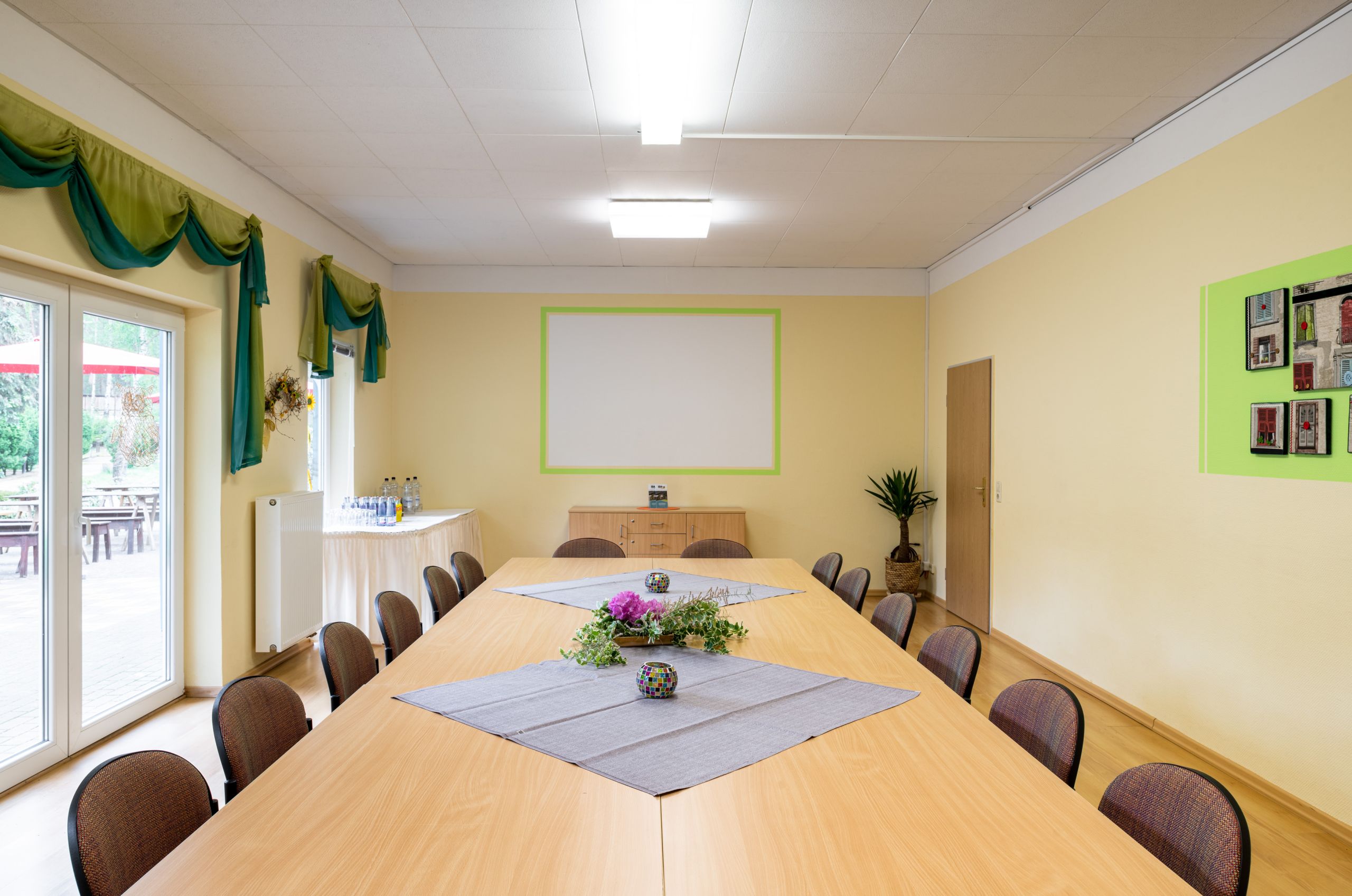 Besprechungsraum mit Leinwand, Tischen, Stühlen, Getränkeauswahl