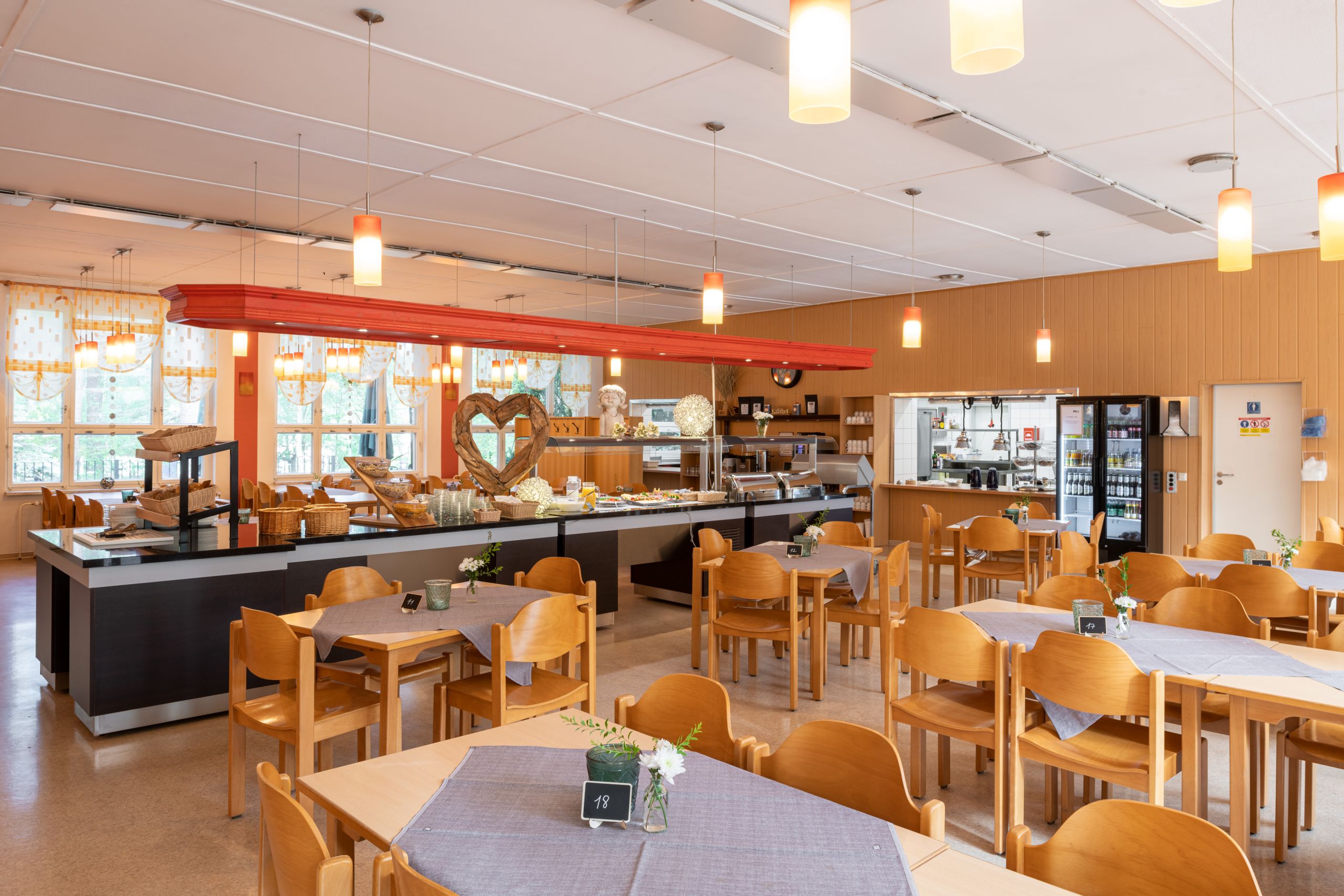 Leere Tische und Stühle im Speisesaal, im Hintergrund ein Buffet
