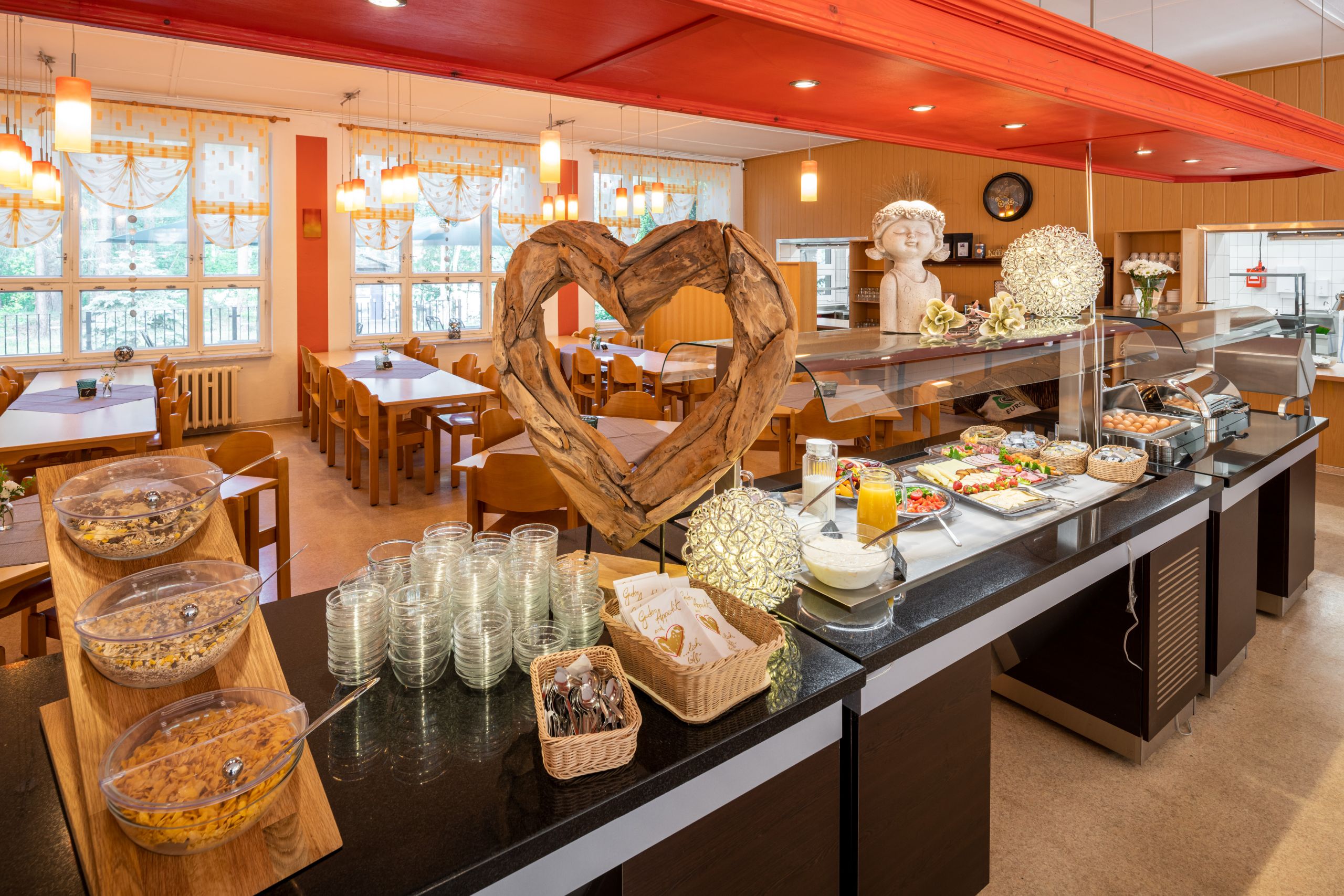 Frühstücksbuffet an einer langen Tafel, im Hintergrund leere Tische und Stühle