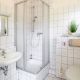 Badezimmer mit weißen Fliesen und Dusche, WC und Waschbecken