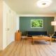 Panoramabild Wohnzimmer, mit Küchenzeile, Sofa, Sessel, Couchtisch und angeschnittenem Esstisch