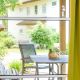 Blick durch ein Terassenfenster auf die terasse, dort stehen Sitzmöbel und ein Tisch mit einer Blume drauf