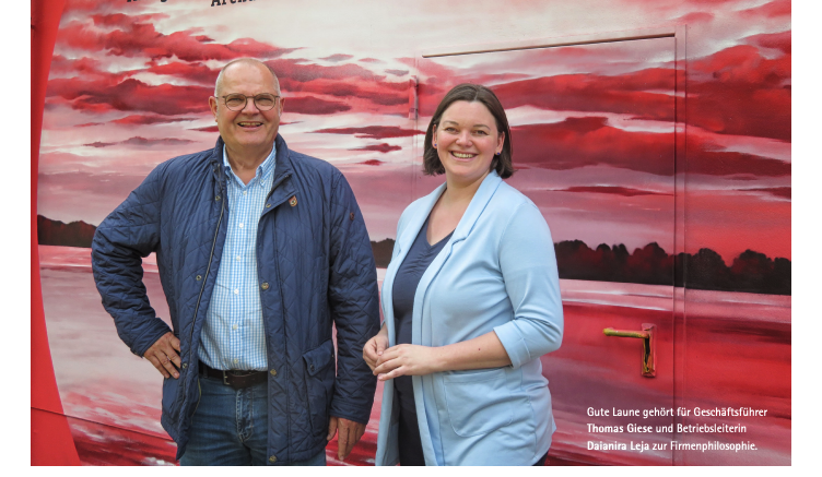 eine Frau und ein Mann stehen vor einer roten Wand
