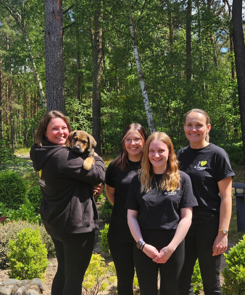 4 Frauen und ein Hund schauen in die Kamera und lächeln